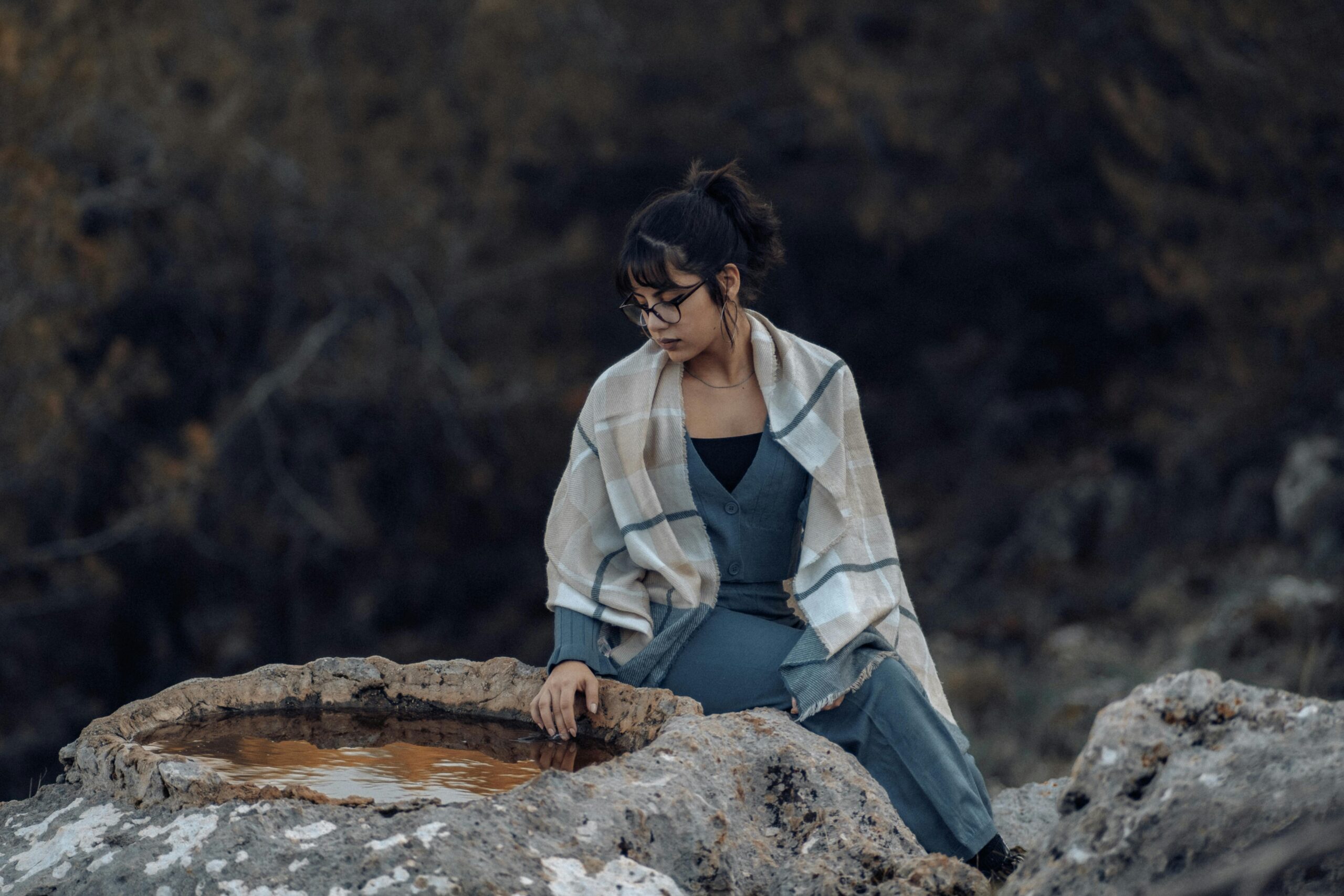 Woman Sitting by a Puddle of Water